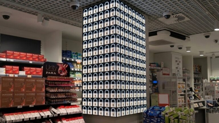 Colonne d'écrans LED diffusant un visuel de cybersécurité (cadenas) en pharmacie